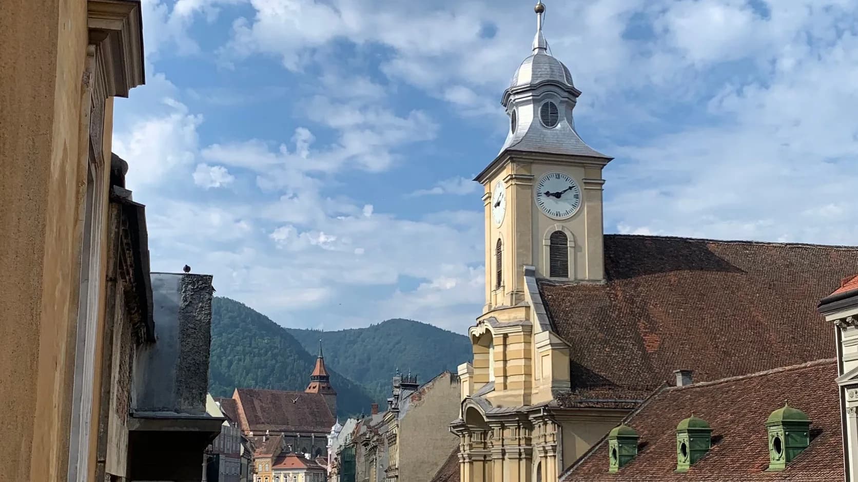 Historic rooftops, a church tower and the Carpathians in Brașov, Romania